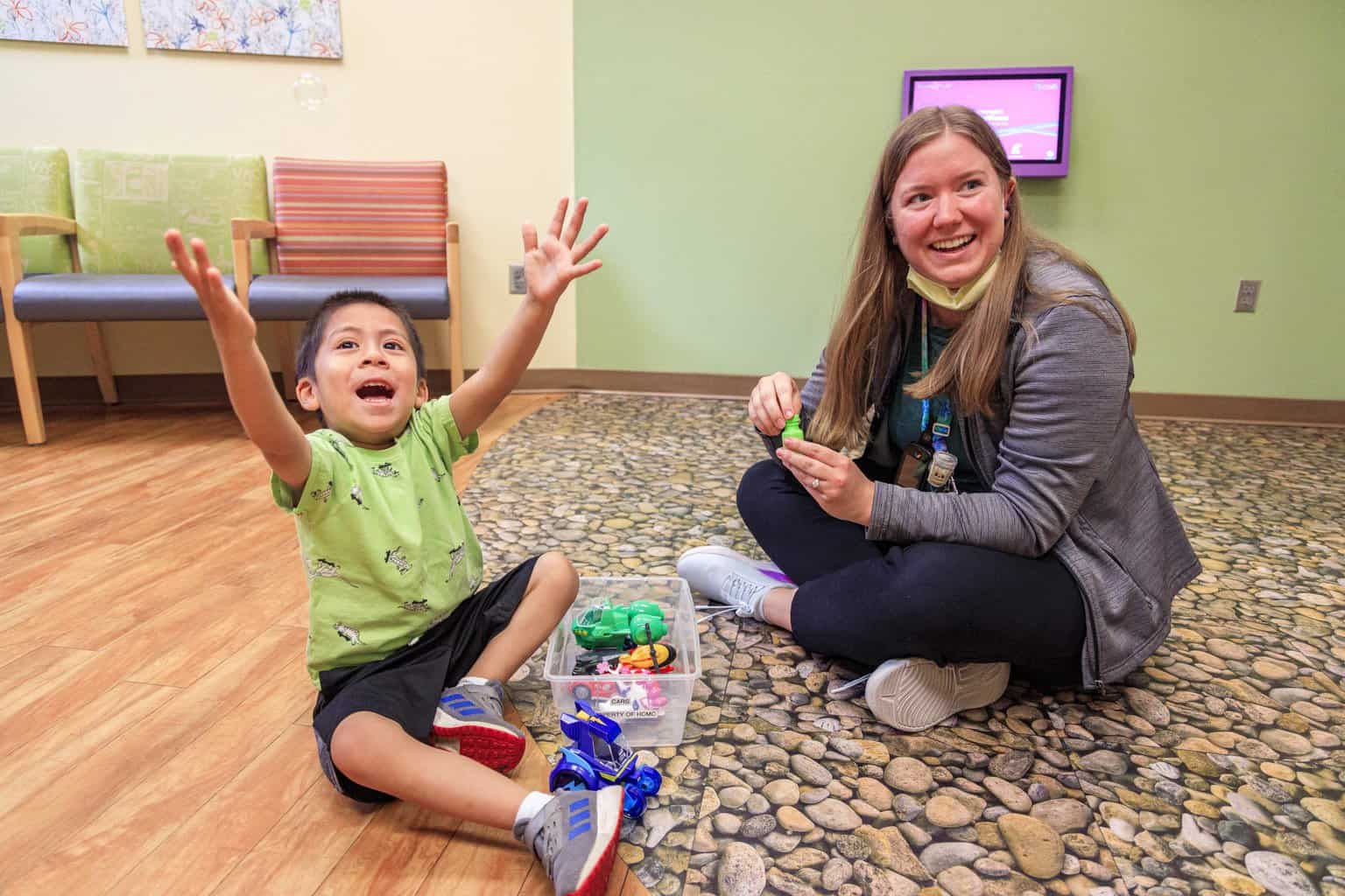 nurse sitting on the floor with a child playing