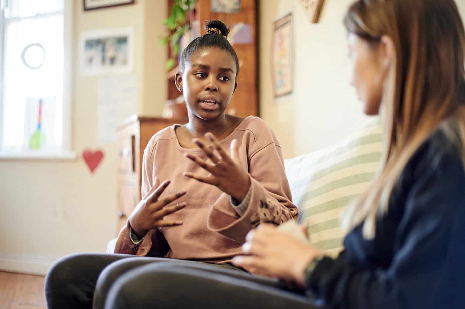 young girl sitting with a female counselor in an office.
