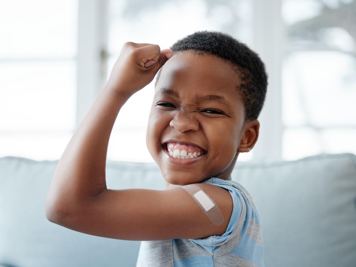 Young black boy proudly showing off his arm where he got a shot/vaccine