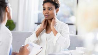 Female patient with hands on next with provider taking notes