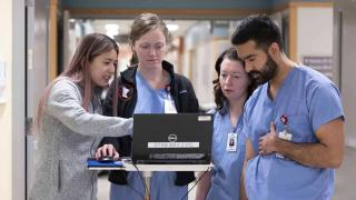 Emergency medical staff standing around a laptop 