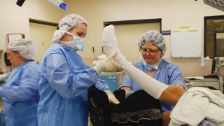 Patient in surgery with providers. Leg being lifted in the air