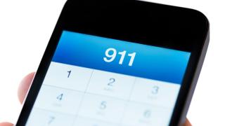 Close-up of a smartphone screen displaying "911" on the dialer interface, indicating an emergency call in progress.