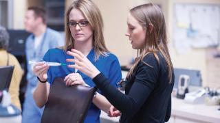 Two nurses consulting one another.