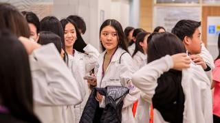 young adults in white lab coats at an event