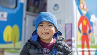young boy standing in front of pediatric mobile van