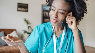 A doctor is communicating with the patient, female doctor is holding a mobile phone and talking, Contact Hennepin Healthcare for clinic appointments, patient representatives, Human Resources, and general hospital information.