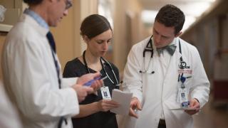 three providers rounding in hospital hallway