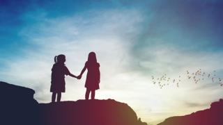 Silhouette of two girls holding hands against a sunset backdrop with birds flying showing hope and a future, loss, cope, grief, fear, dreams, future