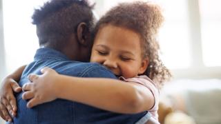 Father daughter embrace with focus on childs happy face, parents, parenting, stress, well-being, mental health, support