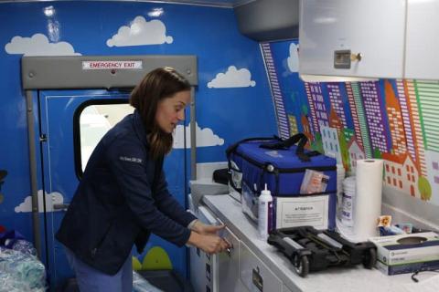 A healthcare provider prepares medical supplies inside the colorful Pediatric Mobile Clinic, which is equipped to deliver care to children in community neighborhoods.