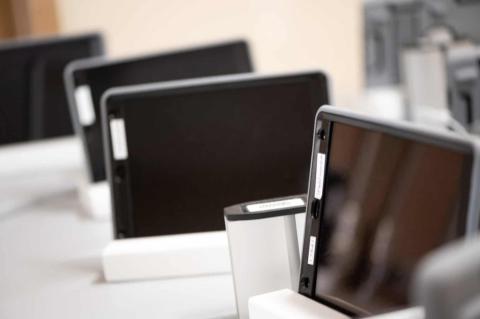 Close-up view of multiple tablet devices docked in charging stations, representing the use of modern technology in healthcare settings.