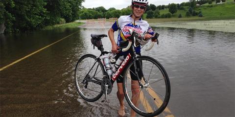 charlene barron on her bike on a flooded road, ironman triathlete, bicycle accident, severe traumatic brain injury, charlene barron, dog run fundraiser, dr uzma samadani, sarah goullaud, dog run at baker park, neck strengthening research