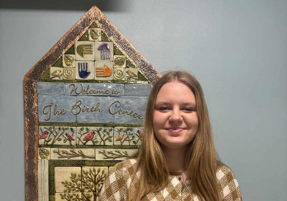 birth center patient iva standing in front of commemorative piece