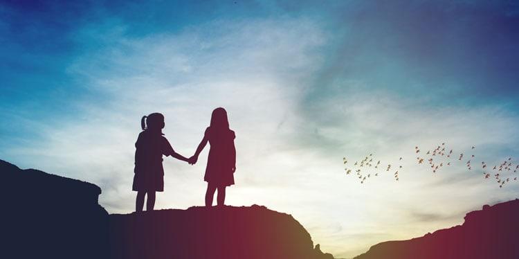Silhouette of two girls holding hands against a sunset backdrop with birds flying showing hope and a future, loss, cope, grief, fear, dreams, future