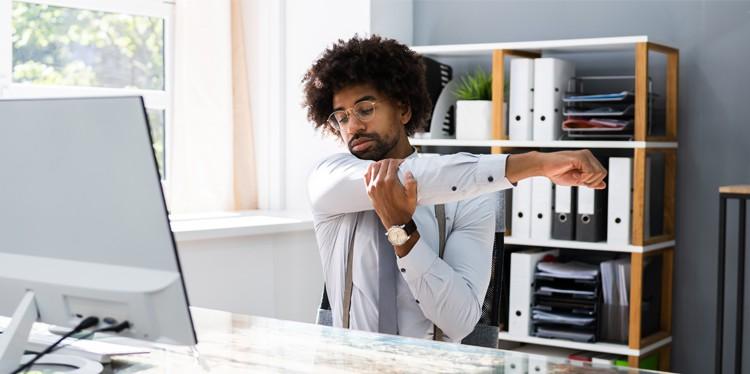 Man Stretching At Desk, pain at work, reduce pain at work, work pain, ways to reduce pain at work