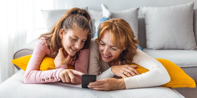 teen girl with mom looking at smartphone together, spending time with your teen, teen support system, healthy relationship with parent and teen, Between Us Understanding My Teen, early adolescence, middle adolescence, late adolescence, mental and physical growth