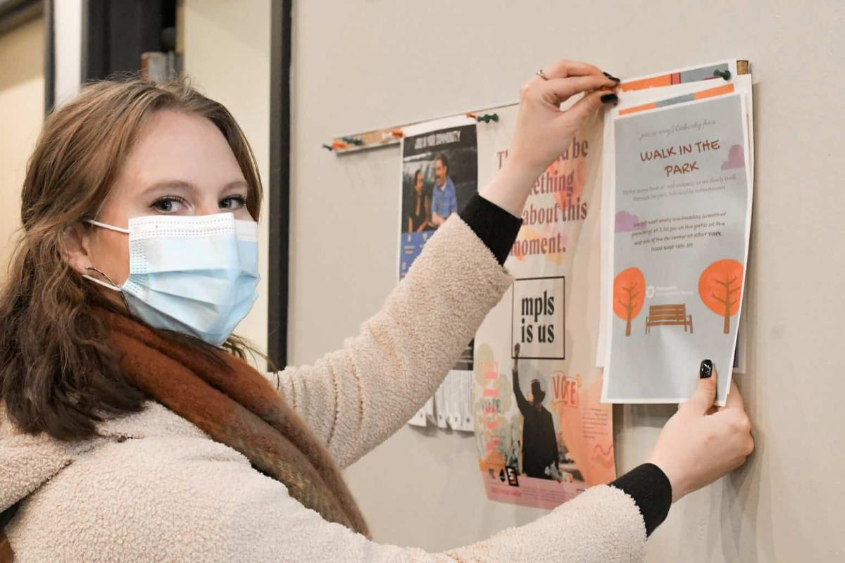 rebecca wearing a mask and posting a community flier, voices of hennepin healthcare, rebecca thomas, elliot park neighborhood, advance health equity in healthcare, systemic change in healthcare