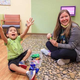 nurse sitting on the floor with a child playing