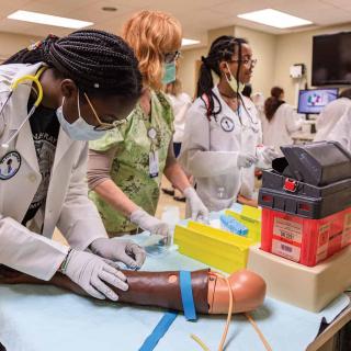 Black Youth with Stethoscopes using training equipment in lab