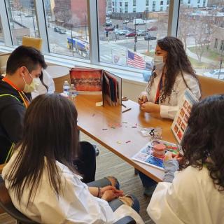 Students seated at a table learning about dental health with tooth models and diagrams.