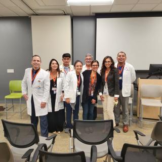 Group of faculty and staff in lab coats posing together at the front of a classroom.