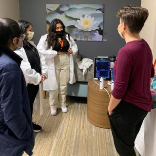 Students gathered around an ultrasound machine for a medical demonstration.