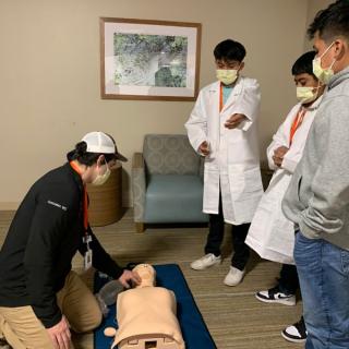 Students learning CPR techniques with a mannequin under instructor guidance.