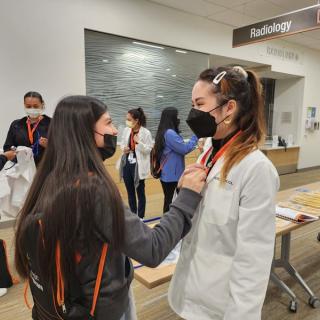 Two students chatting and smiling, one wearing a lab coat.