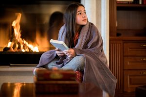 young woman with a book by a fireplace, Carbon monoxide poisoning, risk increases as temperature decreases, preventive measures against carbon monoxide exposure